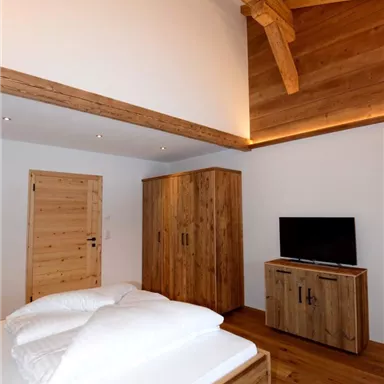 Ein modernes Schlafzimmer mit Holzböden und Holzmöbeln. Die Wände sind hell, und eine große Fensterfläche sorgt für viel Licht.