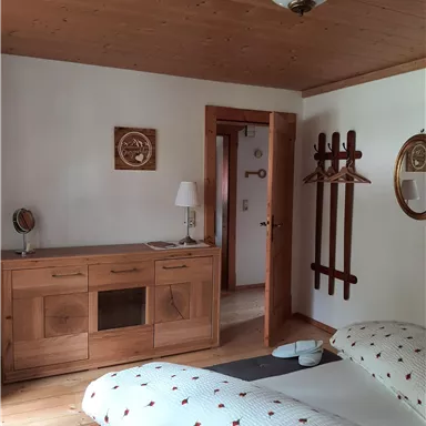 Ein gemütliches Schlafzimmer mit Holzdetails und einem Doppelbett. Es gibt einen Schminktisch und eine Garderobe an der Wand.