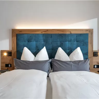 Ein gemütliches Schlafzimmer mit einem Doppelbett und einer geschmackvollen Wandgestaltung. Die Kissen sind sorgfältig arrangiert und schaffen eine einladende Atmosphäre.