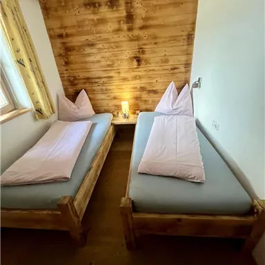 Ein gemütliches Zimmer mit zwei Einzelbetten und Holzverkleidung. Das sanfte Licht schafft eine entspannte Atmosphäre.