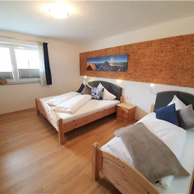 Ein gemütliches Schlafzimmer mit zwei Einzelbetten und Holzverkleidung. Das Zimmer ist hell und freundlich mit großen Fenstern.