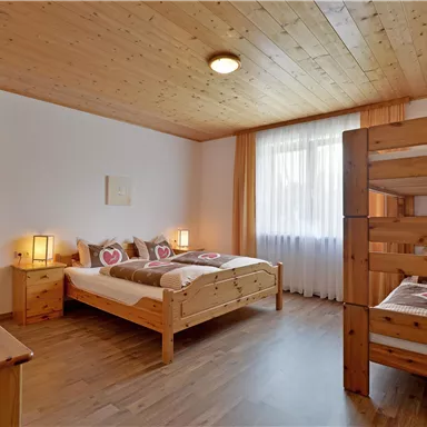 Ein gemütliches Schlafzimmer mit Holzmöbeln und zwei Betten. Das Zimmer hat viel Tageslicht und eine warme Atmosphäre.