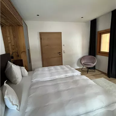 Ein modernes Schlafzimmer mit zwei Einzelbetten und einer gemütlichen Sitzecke. Helle Farben und Holzdetails schaffen eine einladende Atmosphäre.