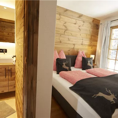 Ein gemütliches Schlafzimmer mit Holzverkleidung und einem modernen Badezimmer. Die Fenster bieten viel Licht und einen schönen Ausblick.