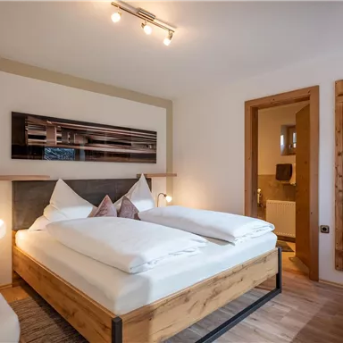 A modern room with a double bed and comfortable furnishings. The space features wooden details and pleasant lighting.