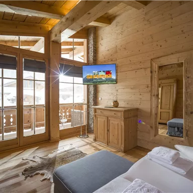 Ein gemütliches Schlafzimmer aus Holz mit großen Fenstern und Balkon. Das Zimmer ist modern eingerichtet und hat eine entspannende Atmosphäre.
