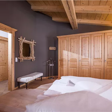 Ein gemütliches Schlafzimmer mit Holzmöbeln und einer warmen Farbgestaltung. Große Fenster sorgen für viel Licht und eine einladende Atmosphäre.