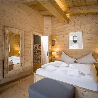 Ein gemütliches Zimmer mit Holzvertäfelungen und einem großen Bett. Es gibt eine Spiegelwand und sanfte Beleuchtung, die eine warme Atmosphäre schafft.