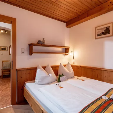 A cozy bedroom with wood paneling and two beds. The room feels inviting and bright, with a warm, rustic character.