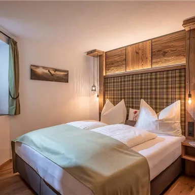 A cozy bedroom with wooden paneling and a large bed. The warm colors and soft lamps create an inviting atmosphere.