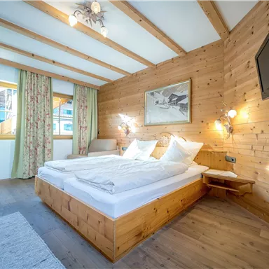 Ein gemütliches Schlafzimmer mit Holzvertäfelung und warmen Farben. Es ist hell und einladend, ausgestattet mit einem Doppelbett und einem Fernseher.