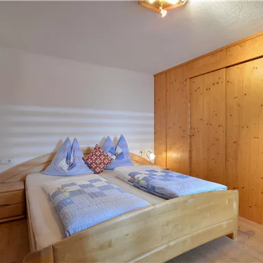 Ein gemütliches Schlafzimmer mit einem Doppelbett und Holzverkleidung. Die Wände sind hell, und es gibt eine angenehme Atmosphäre.