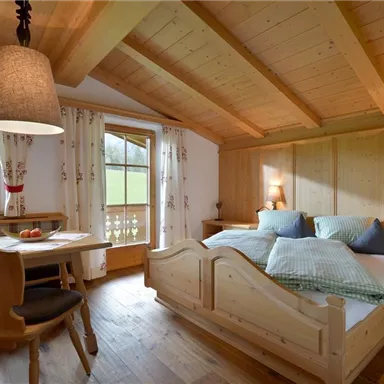 Ein gemütliches Schlafzimmer mit Holzdekor und einem Doppelbett. Fenster bieten einen Blick auf die grüne Landschaft.