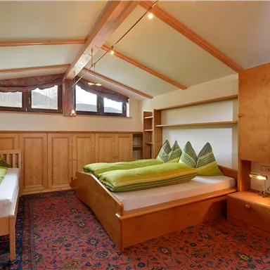 A cozy bedroom with two beds and a large window. The walls are made of wood and there is a warm, welcoming atmosphere.