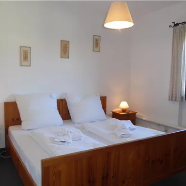 A cozy bedroom with a double bed and wooden planks. The room is bright and friendly, featuring a window and nightlights.