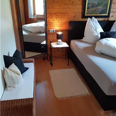 A cozy room with a large bed and wooden paneling. A mirror and a table next to the bed complete the furnishings.