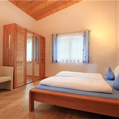 Ein helles und gemütliches Schlafzimmer mit Holzmöbeln. Das Zimmer verfügt über ein Doppelbett, ein Nachttisch und einen Kleiderschrank.