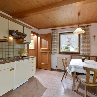 Eine gemütliche Küche mit Holzdecken und einem Essbereich. Die Einrichtung ist einfach und einladend.