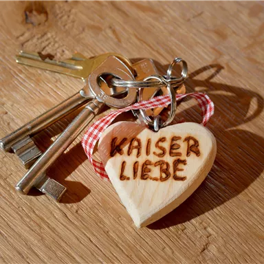 Ein Schlüsselbund mit einem Holzanhänger in Herzform. Auf dem Anhänger steht "KAISER LIEBE".