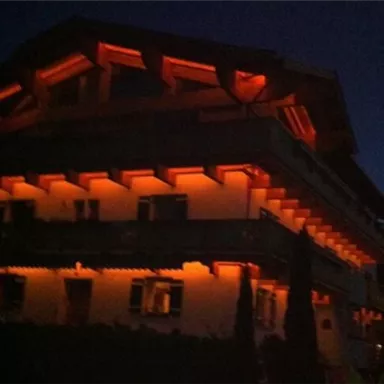 Ein schön beleuchtetes Gebäude bei Nacht. Die orangefarbene Beleuchtung hebt die architektonischen Details hervor.