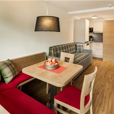 A modern living kitchen with a dining table and comfortable seating options. The furnishings are bright and inviting with wooden floors and minimalist decoration.