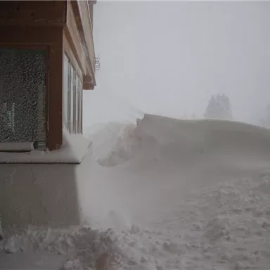 A snowy landscape picture with deep snow pressing against the window. Visibility is limited due to heavy snowfall.