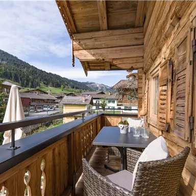 Ein gemütlicher Balkon mit Holzverkleidung und Blick auf eine malerische Berglandschaft. Auf dem Tisch steht eine Dekoration, ideal für entspannte Stunden im Freien.