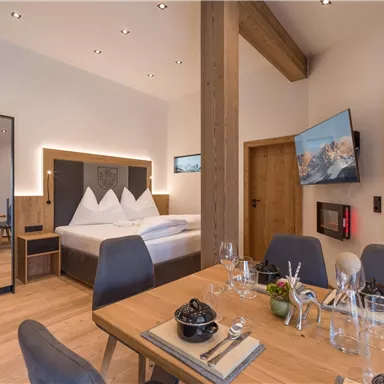 Ein stilvolles Zimmer mit einem großen Bett und modernem Mobiliar. Der Essbereich ist elegant dekoriert und bietet Platz für mehrere Personen.