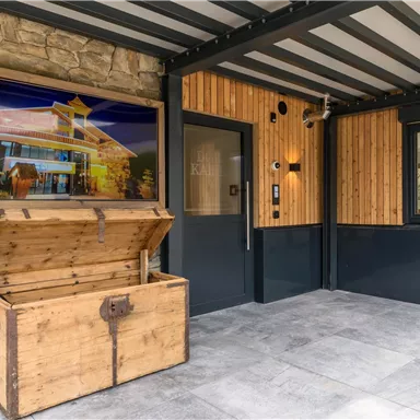 Ein einladender Eingangsbereich mit einem Holzkasten und einem großen Bild an der Wand. Die Wände sind aus Holz und Stein, was eine gemütliche Atmosphäre schafft.