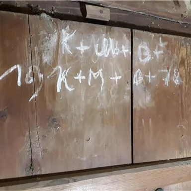 A wooden surface with handwritten characters and formulas in white color. The contents seem to be mathematical notations or notes.