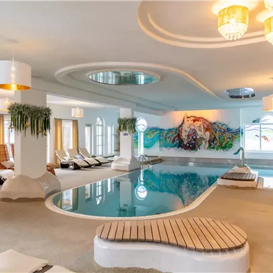 Ein eleganter Innenpool mit modernen Liegen und dekorativen Wänden. Das Umfeld ist hell und einladend, mit großen Fenstern und sanfter Beleuchtung.