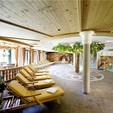 A relaxing wellness area with loungers and a pool. The surroundings are bright and friendly, with plants and a cozy atmosphere.