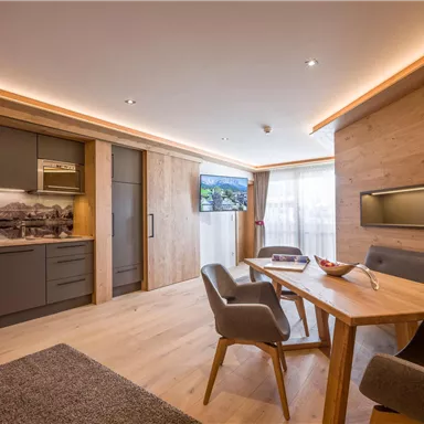 Modern apartment with open kitchen and wooden furniture. Bright atmosphere with large windows and a stylish color concept.