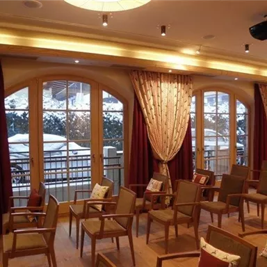 A bright room with wooden floor and rows of chairs. Large windows offer a view of a snowy landscape.