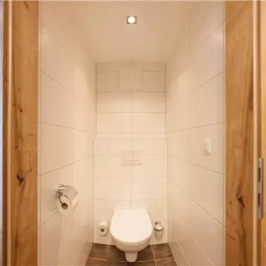 Ein modernes Badezimmer mit einer weißen Toilette und hellen Wänden. Der Raum ist gut beleuchtet und hat einen minimalistischen Stil.