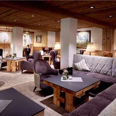 A cozy interior with modern furniture and warm wood tones. The lighting creates a relaxed atmosphere for social gatherings.