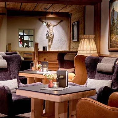 A cozy lounge area with comfortable armchairs and a wooden table. The warm lights and wooden-paneled walls create an inviting atmosphere.