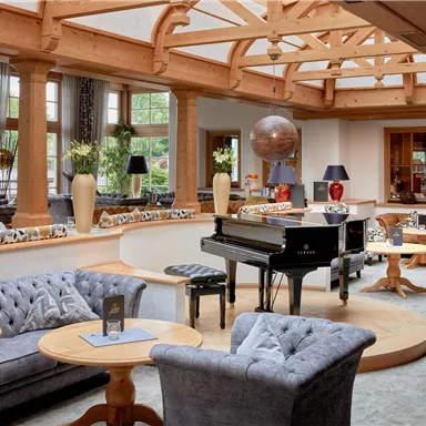 An elegant living room with a piano in the center. Cozy sofas and chairs create an inviting atmosphere.