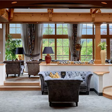 An elegant living room with cozy sofas and large windows. The high ceilings and stylish lamps create an inviting atmosphere.