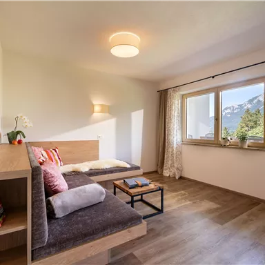 Ein helles Wohnzimmer mit modernem Design und einem bequemen Sofa. Große Fenster bieten einen Blick auf die Berge.