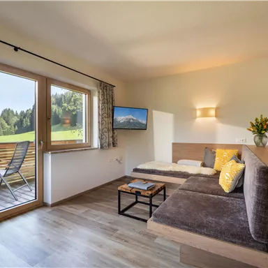 Eine gemütliche Wohnung mit einem modernen Wohnbereich. Große Fenster bieten einen schönen Blick auf die Landschaft.