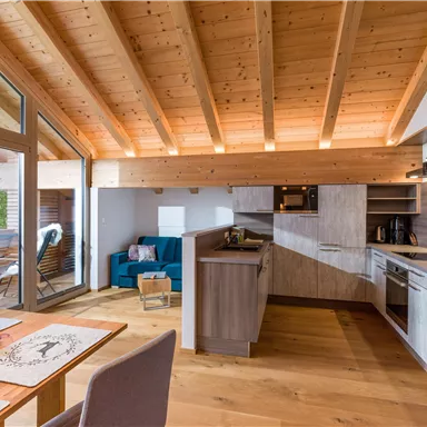 Eine moderne, helle Wohnung mit Holzdecke und offenen Raum. Die Küche ist gut ausgestattet und es gibt einen gemütlichen Wohnbereich.