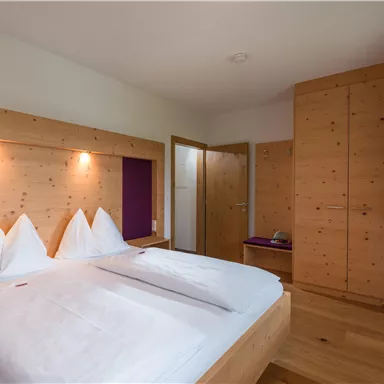 Ein modernes Schlafzimmer mit Holzverkleidung und einem Doppelbett. Die Wände sind hell und der Raum wirkt gemütlich und einladend.