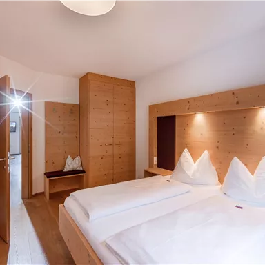 Ein gemütliches Schlafzimmer mit zwei Betten und modernem Holzmobiliar. Der Raum ist hell erleuchtet und hat eine einladende Atmosphäre.