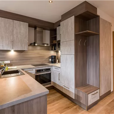 Eine moderne Küche mit Holzfronten und eleganten Oberflächen. Sie ist gut ausgestattet mit einem Herd, einem Ofen und einem Platz für Ablage.