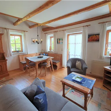 Ein einladendes Wohnzimmer mit holzverkleideten Wänden und einem großen Esstisch. Helle Fenster sorgen für eine freundliche Atmosphäre.