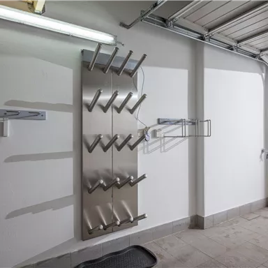 Ein moderner Speicherplatz in einer Garage mit einem Gestell zur Aufbewahrung von Sportgeräten. Der Raum ist hell und aufgeräumt, mit einem Blick auf schneebedeckte Außenbereiche.