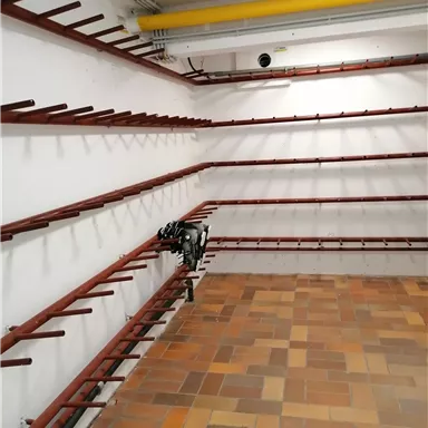 An empty room with red shelves on the wall. The floor is tiled with brown tiles.