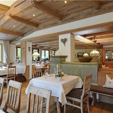 Ein gemütliches Restaurant mit Holzmöbeln und warmem Licht. Die Tische sind für Gäste gedeckt und bieten eine einladende Atmosphäre.