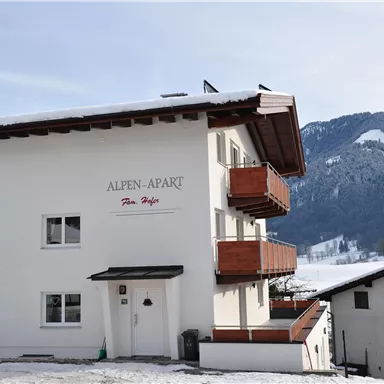 A modern apartment building in the snow called "Alpen-Apart." Picturesque mountains can be seen in the background.